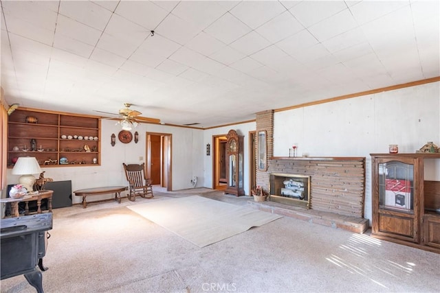 carpeted living room featuring ceiling fan, ornamental molding, and a fireplace