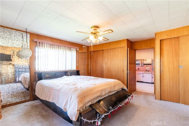 carpeted bedroom featuring ceiling fan and wood walls