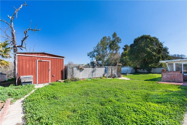 view of yard with a storage shed, fence, and an outbuilding