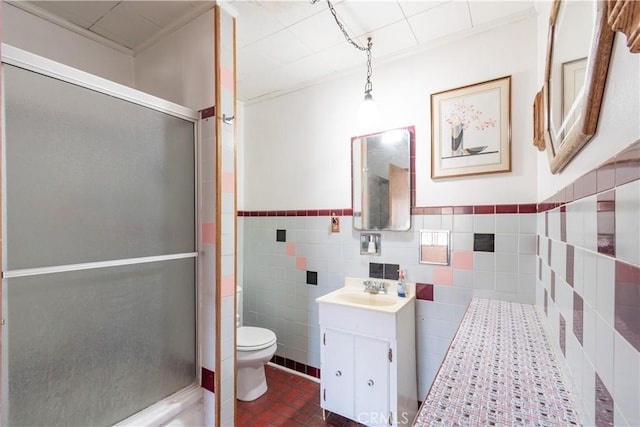 bathroom featuring toilet, vanity, a shower stall, and tile walls