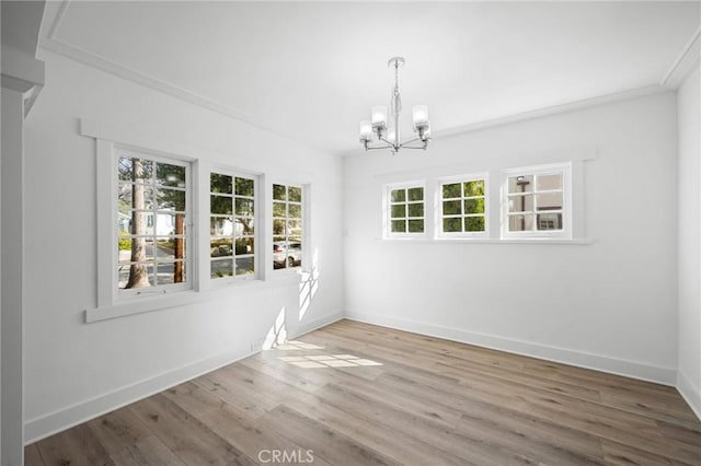 unfurnished dining area with an inviting chandelier, baseboards, and wood finished floors