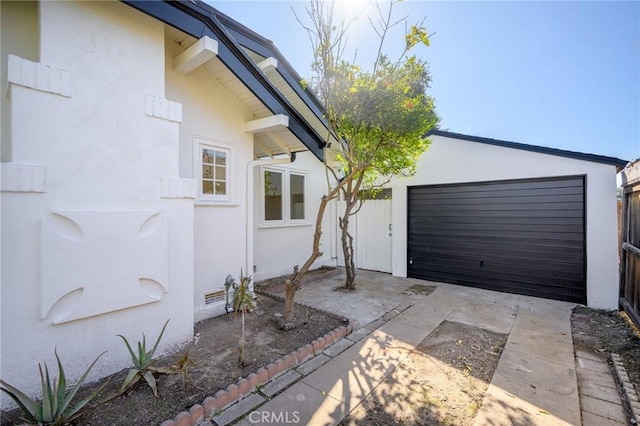 view of side of property with a garage, crawl space, driveway, and stucco siding