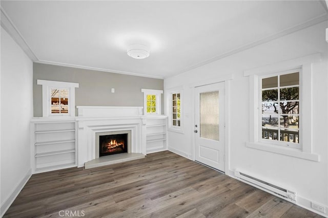 unfurnished living room featuring crown molding, baseboard heating, wood finished floors, a lit fireplace, and baseboards