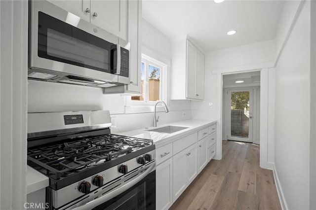 kitchen featuring stainless steel appliances, white cabinets, light countertops, and a sink