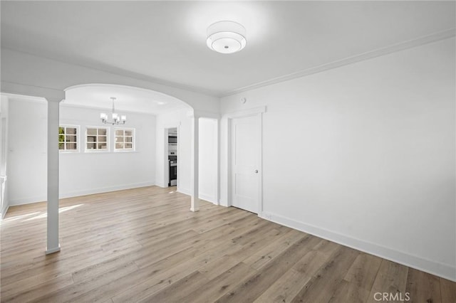 unfurnished living room featuring arched walkways, baseboards, light wood finished floors, and an inviting chandelier