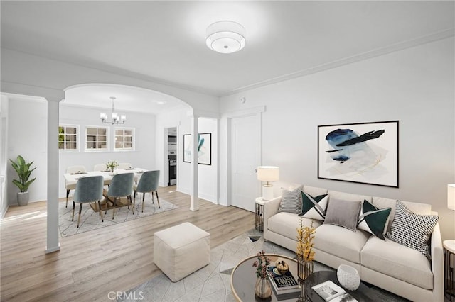 living room with light wood-type flooring, arched walkways, and a notable chandelier