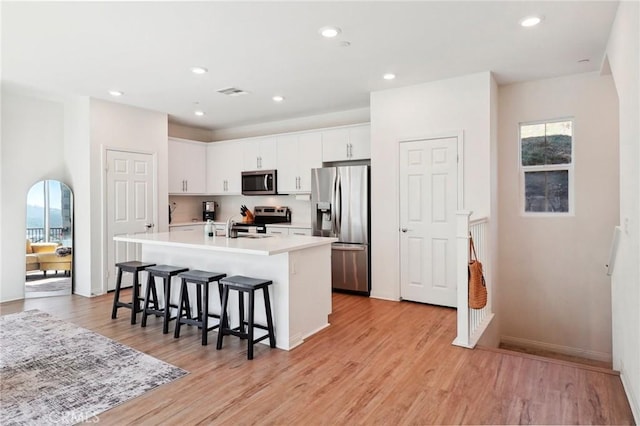 kitchen with a kitchen island with sink, white cabinetry, stainless steel appliances, and light countertops