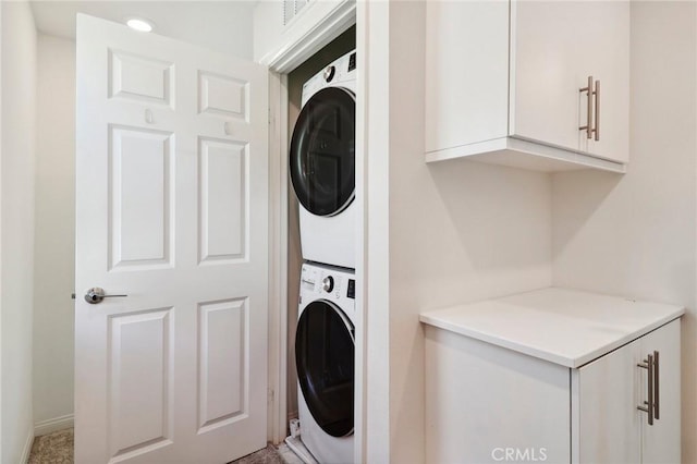 laundry area with laundry area, visible vents, and stacked washer / drying machine