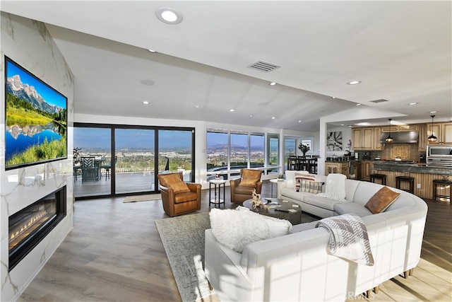 living area featuring a high end fireplace, visible vents, and recessed lighting