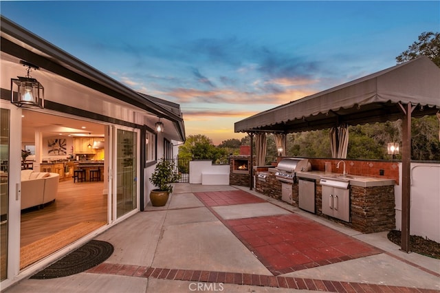 view of patio with an outdoor kitchen, a gazebo, grilling area, and a wooden deck