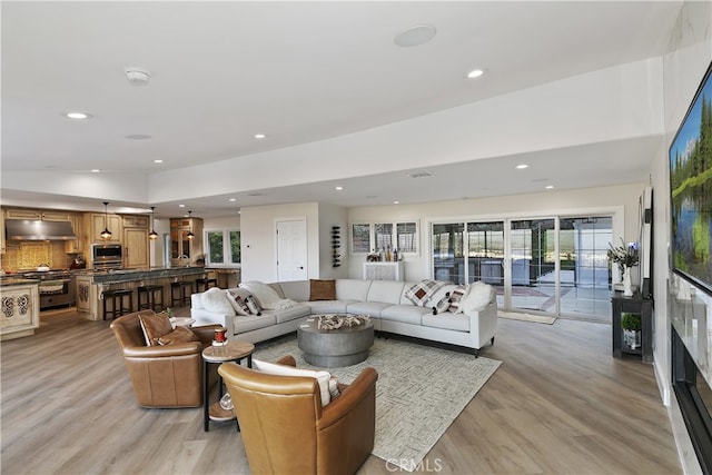 living room featuring light wood-type flooring, plenty of natural light, and lofted ceiling