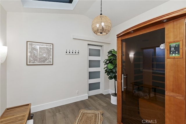 hall featuring baseboards, dark wood finished floors, a sauna, an inviting chandelier, and vaulted ceiling