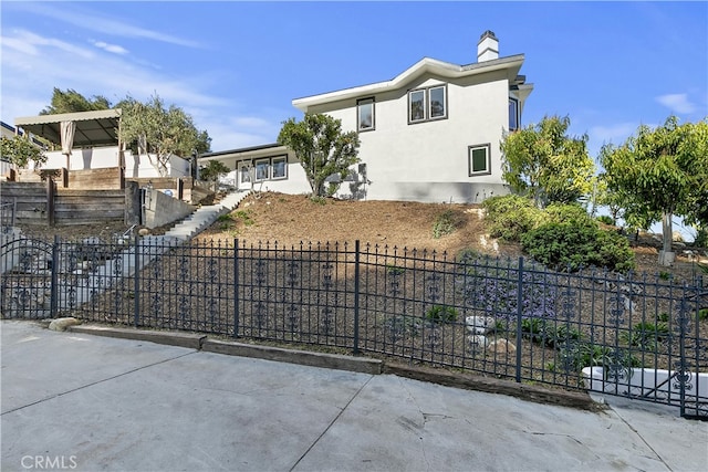 view of front of house featuring a chimney, a fenced front yard, and stucco siding