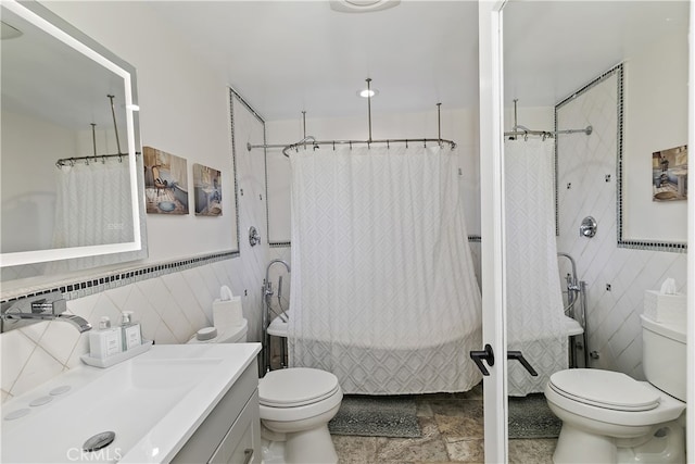 bathroom with toilet, vanity, tile walls, and a combined bath / shower with rainfall shower