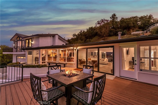 deck at dusk featuring an outdoor fire pit