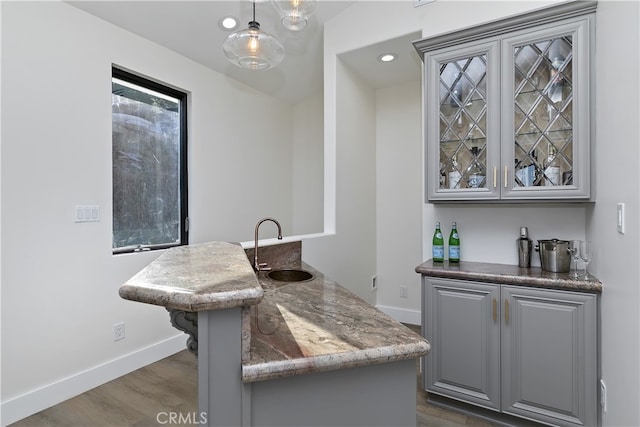 bar featuring dark wood-style floors, baseboards, a sink, and wet bar