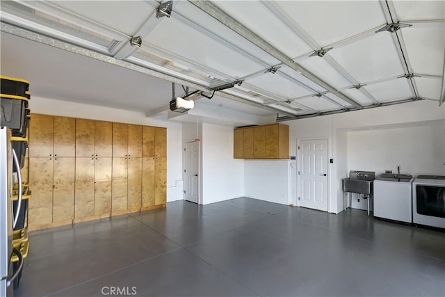 garage with a garage door opener, freestanding refrigerator, a sink, and washing machine and clothes dryer