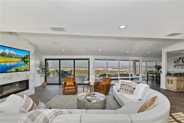 living room featuring a fireplace, visible vents, dark wood-style flooring, and recessed lighting