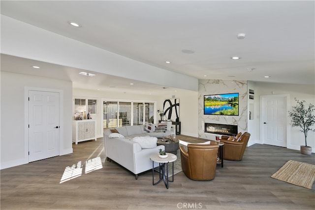 living area with a high end fireplace, vaulted ceiling, recessed lighting, and wood finished floors