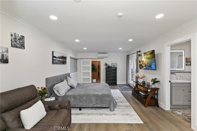 bedroom featuring recessed lighting, a barn door, ornamental molding, an AC wall unit, and wood finished floors