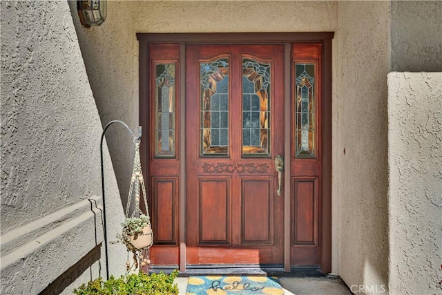 doorway to property featuring stucco siding