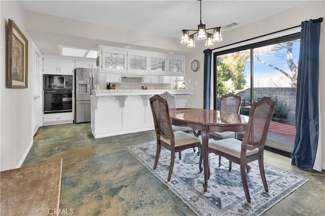 dining area featuring visible vents, concrete floors, baseboards, and an inviting chandelier