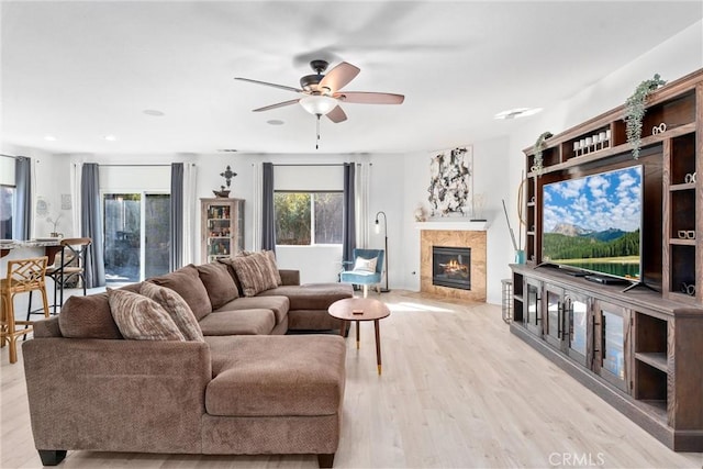 living room with light wood-type flooring, a fireplace, and ceiling fan