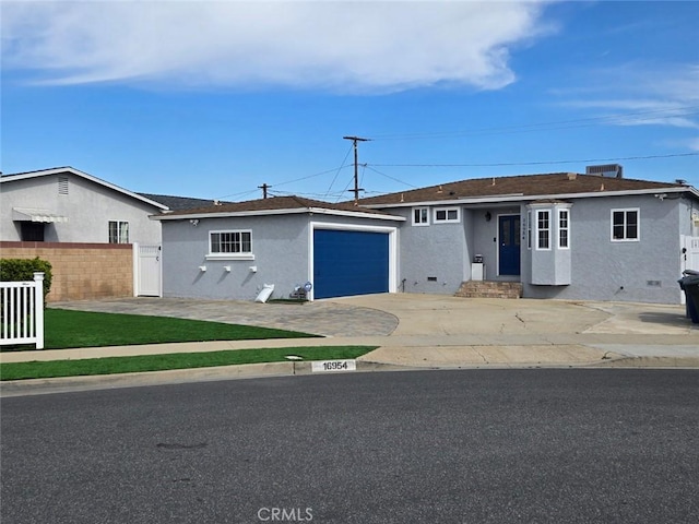 ranch-style house featuring stucco siding, concrete driveway, a garage, and fence