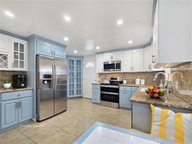 kitchen with tasteful backsplash, stainless steel appliances, glass insert cabinets, and a sink