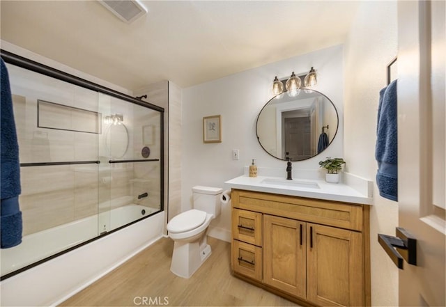 full bathroom featuring shower / bath combination with glass door, visible vents, toilet, vanity, and wood finished floors