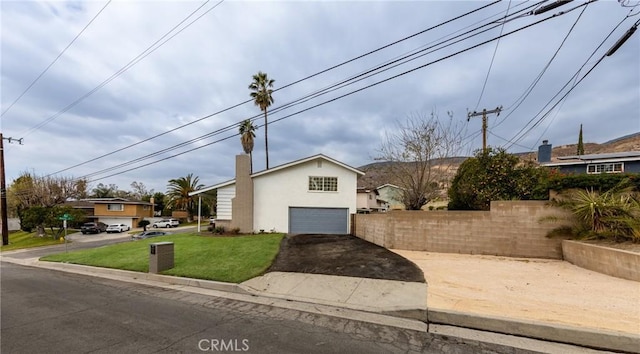 view of front facade with a chimney, stucco siding, a front yard, a garage, and driveway