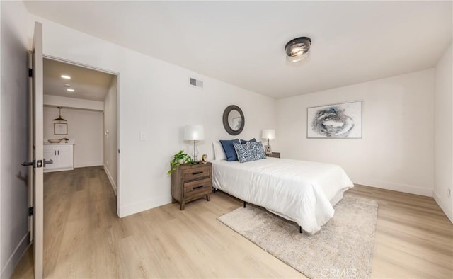 bedroom with visible vents, baseboards, and wood finished floors