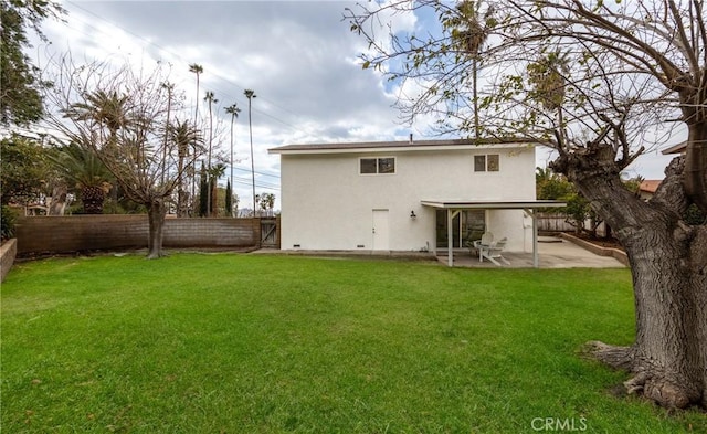 rear view of house featuring a yard, a patio, a fenced backyard, and stucco siding