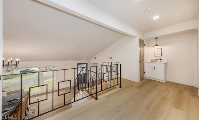 additional living space featuring recessed lighting, a notable chandelier, baseboards, vaulted ceiling, and light wood-style floors