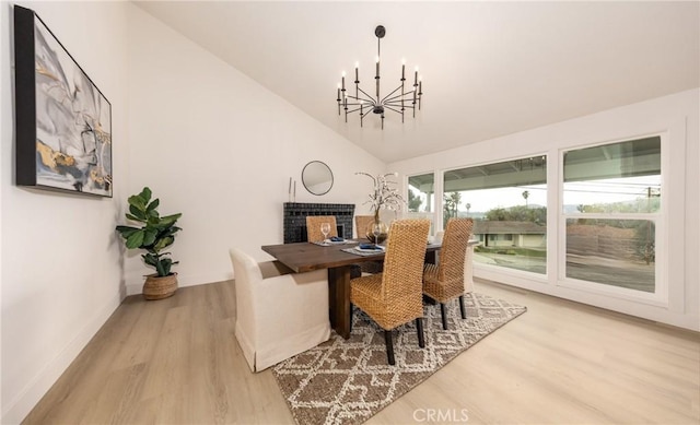 dining area with lofted ceiling, light wood-style floors, baseboards, and a chandelier