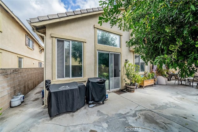 rear view of house with a patio area, stucco siding, and fence