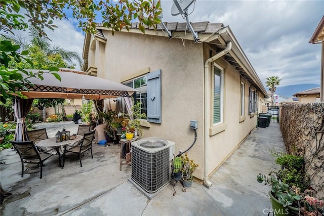 back of house with fence, central air condition unit, a gazebo, stucco siding, and a patio