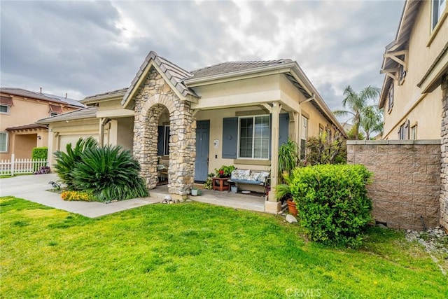 view of front facade featuring fence, concrete driveway, a front yard, stucco siding, and stone siding