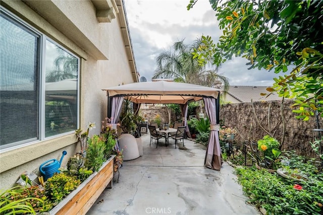 view of patio / terrace featuring a gazebo, outdoor dining space, and fence