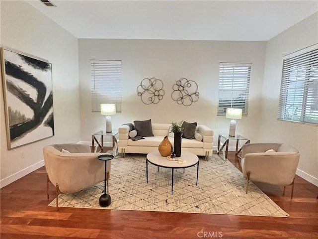 living room featuring visible vents, baseboards, and wood finished floors