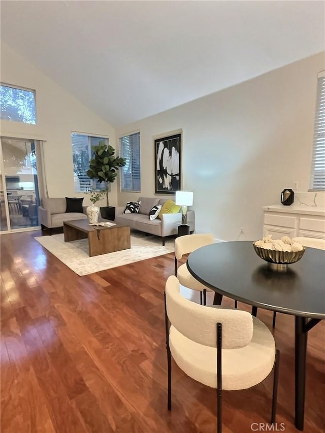 dining area featuring high vaulted ceiling and wood finished floors