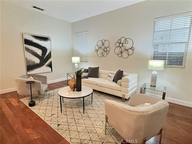 living area featuring wood finished floors, visible vents, and baseboards