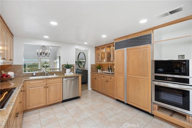 kitchen with visible vents, hanging light fixtures, glass insert cabinets, a sink, and black appliances