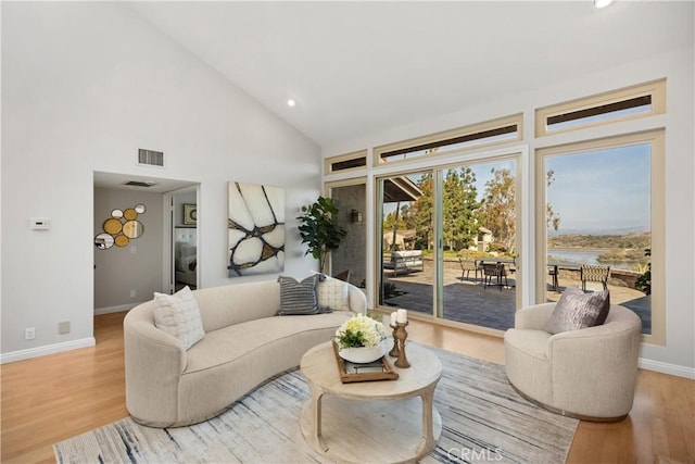 living room featuring visible vents, stacked washer / dryer, wood finished floors, high vaulted ceiling, and baseboards