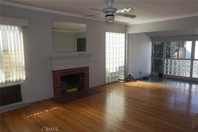 unfurnished living room featuring ornamental molding, a wall unit AC, wood finished floors, and a brick fireplace