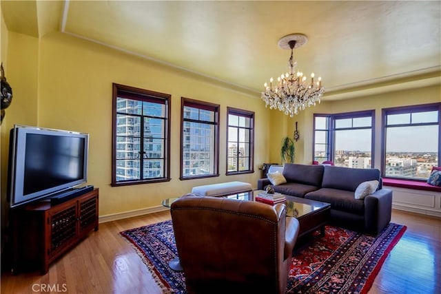 living area with baseboards, an inviting chandelier, and wood finished floors