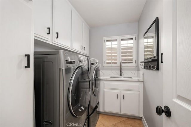 washroom featuring cabinet space, washing machine and dryer, light tile patterned floors, and a sink