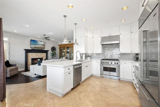 kitchen with under cabinet range hood, open floor plan, premium appliances, and light countertops