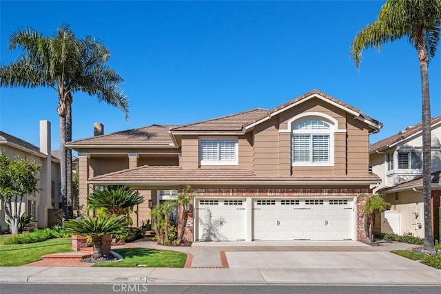 traditional-style house featuring driveway, an attached garage, and a tile roof