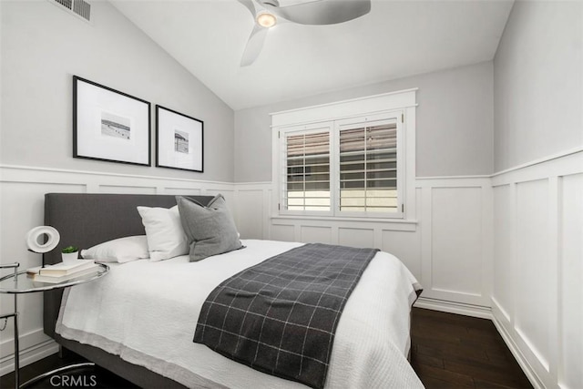 bedroom with visible vents, a ceiling fan, wainscoting, dark wood-type flooring, and vaulted ceiling